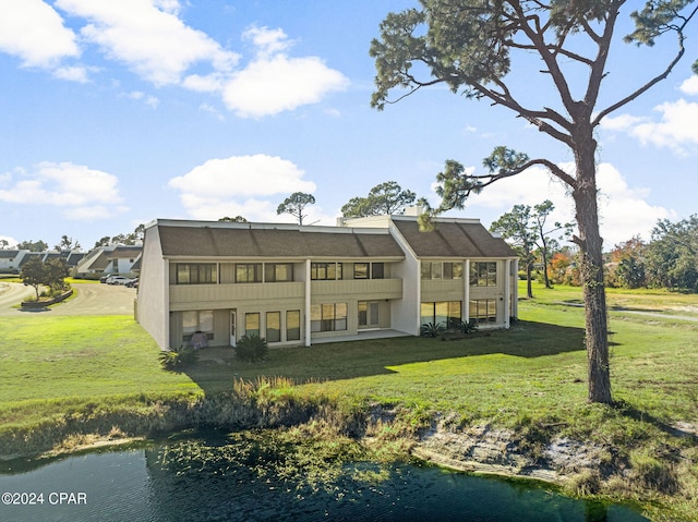 rear view of house featuring a water view, a yard, a balcony, and stucco siding