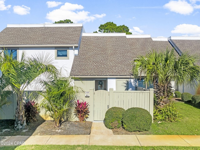 view of front of home with a shingled roof, fence, and a gate