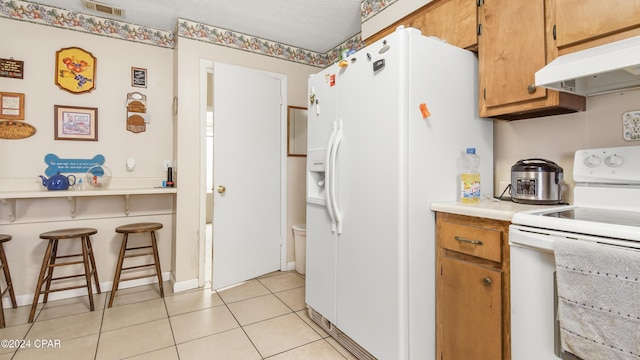 kitchen featuring light tile patterned floors and white appliances