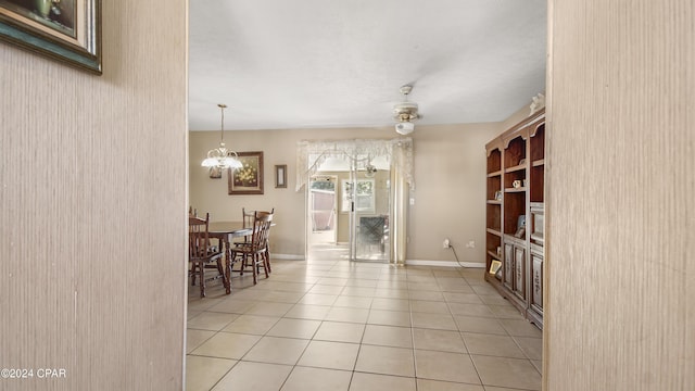 tiled dining space with ceiling fan with notable chandelier