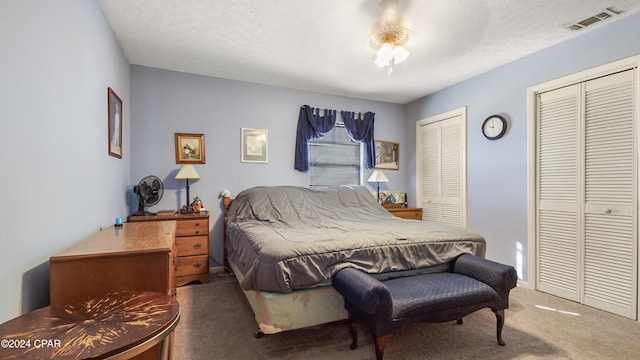 carpeted bedroom featuring two closets and a textured ceiling