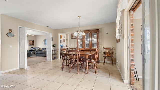 dining space with light tile patterned floors and ceiling fan with notable chandelier