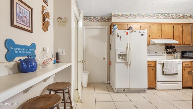 kitchen featuring a textured ceiling, light tile patterned floors, and white appliances