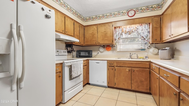 kitchen featuring sink, white appliances, a textured ceiling, and light tile patterned flooring