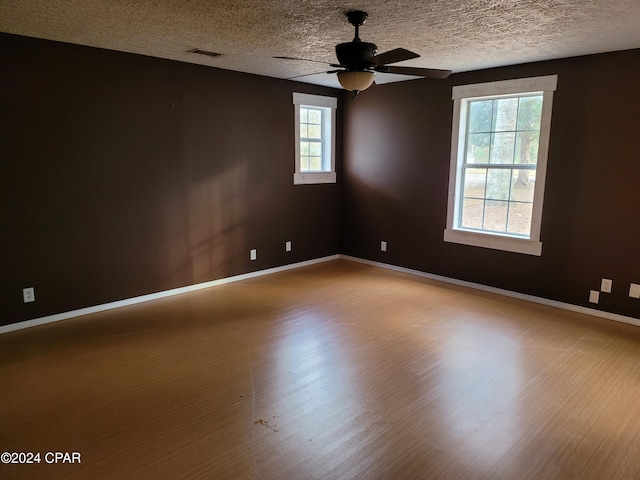 unfurnished room with ceiling fan, a healthy amount of sunlight, a textured ceiling, and hardwood / wood-style flooring