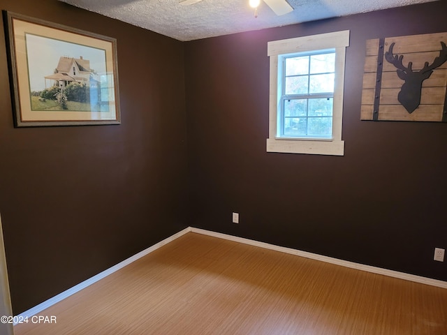 unfurnished room featuring ceiling fan, wood-type flooring, and a textured ceiling