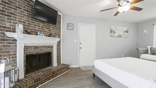 bedroom featuring ceiling fan, dark hardwood / wood-style flooring, and a fireplace