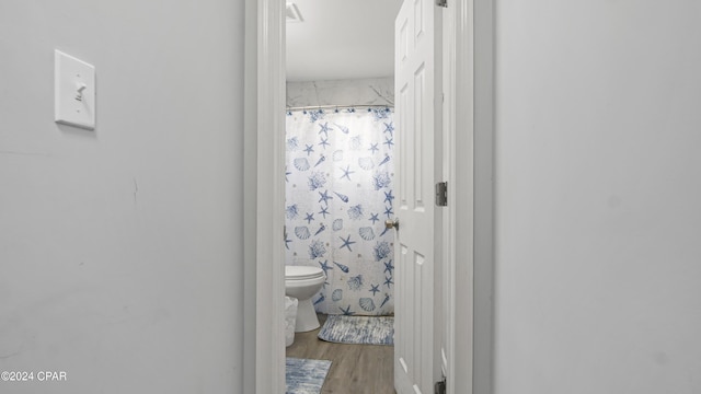 bathroom featuring a shower with curtain, wood-type flooring, and toilet