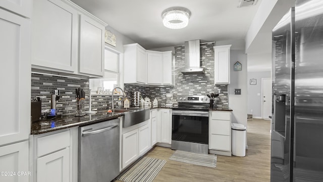 kitchen featuring white cabinets, wall chimney exhaust hood, and appliances with stainless steel finishes