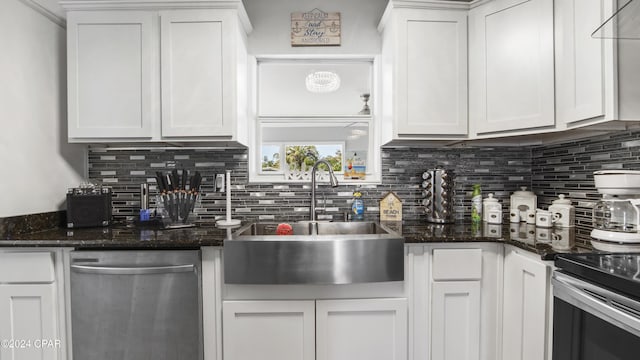 kitchen with dishwasher, white cabinetry, dark stone countertops, and sink