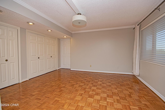 unfurnished bedroom featuring a textured ceiling, ornamental molding, two closets, and light parquet flooring