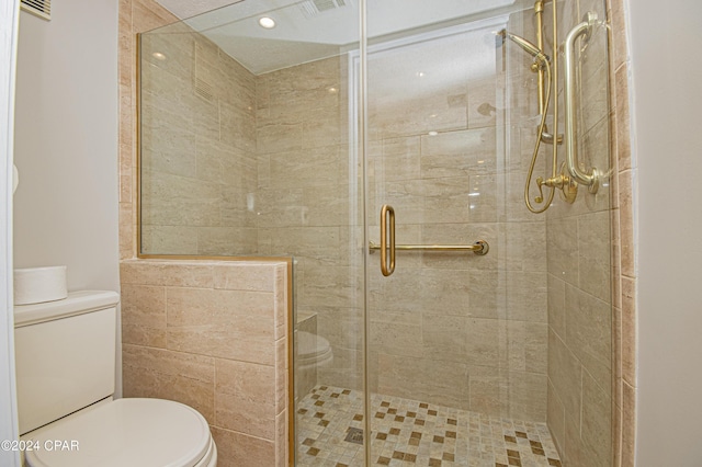 bathroom featuring toilet and a shower with door