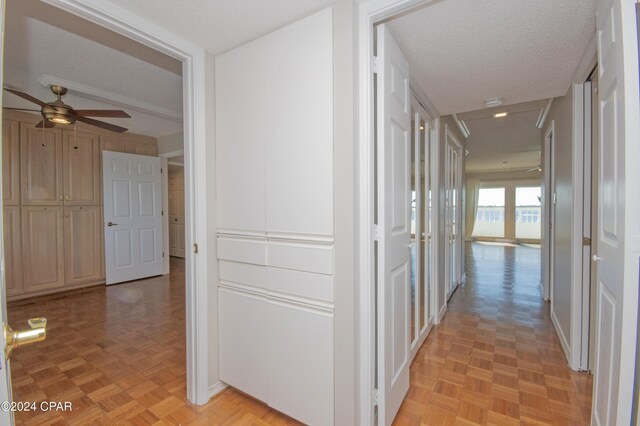 corridor with light parquet flooring and a textured ceiling