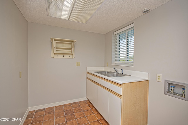 clothes washing area featuring washer hookup, a textured ceiling, cabinets, and sink