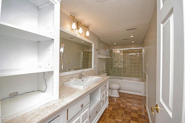 full bathroom featuring toilet, a textured ceiling, parquet flooring, shower / bath combination with glass door, and vanity