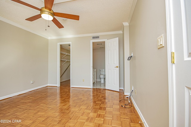 unfurnished bedroom featuring a walk in closet, light parquet flooring, ceiling fan, and crown molding