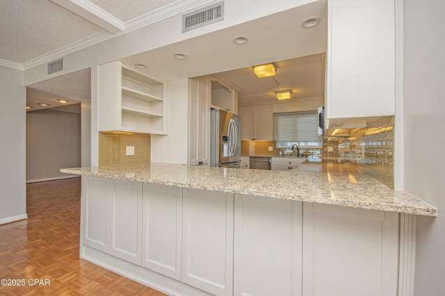 kitchen with light stone counters, stainless steel appliances, kitchen peninsula, and white cabinetry