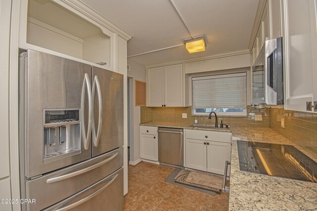 kitchen with light stone counters, decorative backsplash, white cabinetry, appliances with stainless steel finishes, and sink