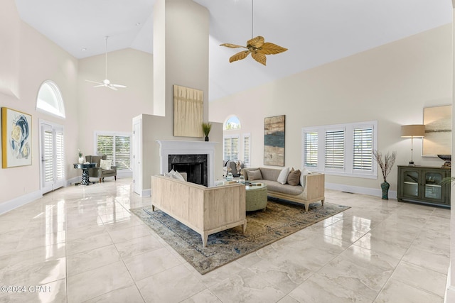 living room featuring ceiling fan, a fireplace, and a high ceiling