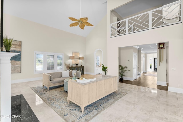 living room with ceiling fan and a towering ceiling