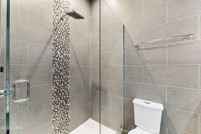 bathroom featuring a shower with shower door and toilet