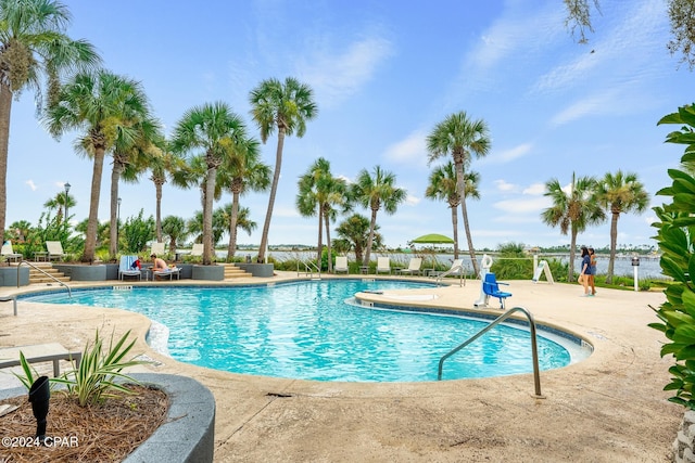 view of swimming pool featuring a water view and a patio