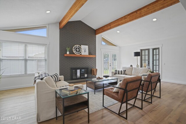 living room with lofted ceiling with beams, light wood-style floors, a brick fireplace, and french doors