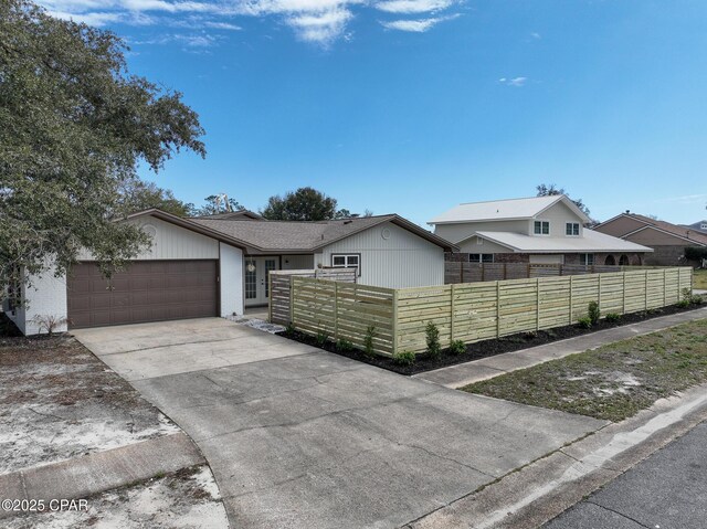 view of front of house featuring a fenced front yard, concrete driveway, brick siding, and an attached garage