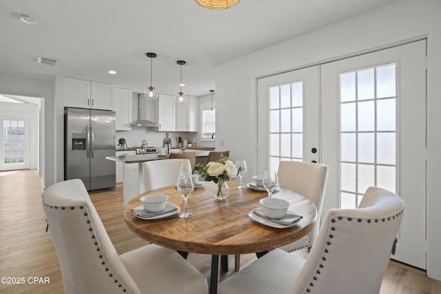 dining room featuring light wood-type flooring, french doors, and a healthy amount of sunlight