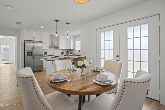 dining room featuring light wood-type flooring, french doors, and a healthy amount of sunlight