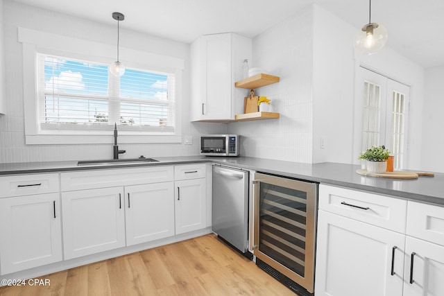 kitchen with wine cooler, light wood-style flooring, a sink, stainless steel microwave, and dark countertops