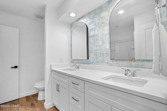 full bathroom with toilet, visible vents, a sink, and wood finished floors