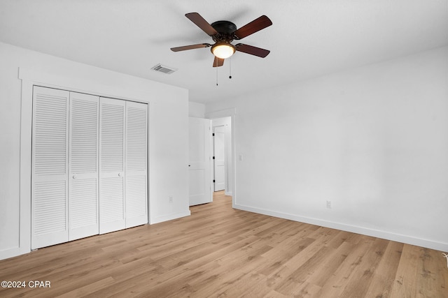 unfurnished bedroom featuring baseboards, visible vents, ceiling fan, light wood-style floors, and a closet