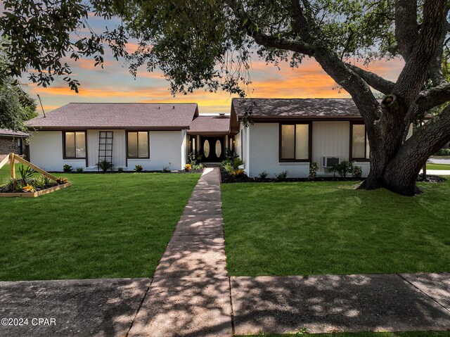 mid-century inspired home with a front lawn, a vegetable garden, and brick siding