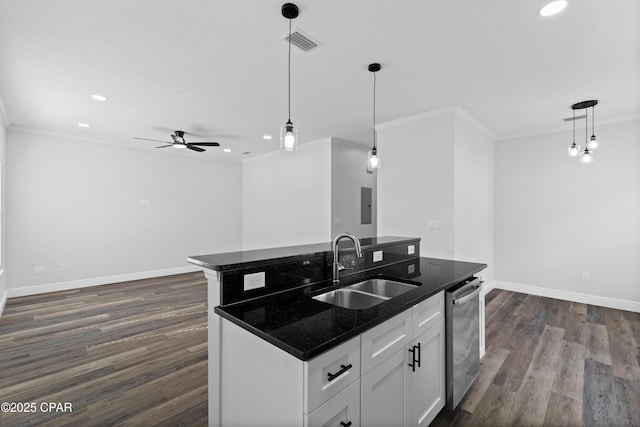 kitchen with sink, hanging light fixtures, white cabinets, and a center island with sink