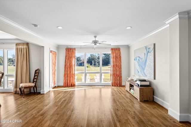 unfurnished living room with baseboards, ornamental molding, ceiling fan, and wood finished floors