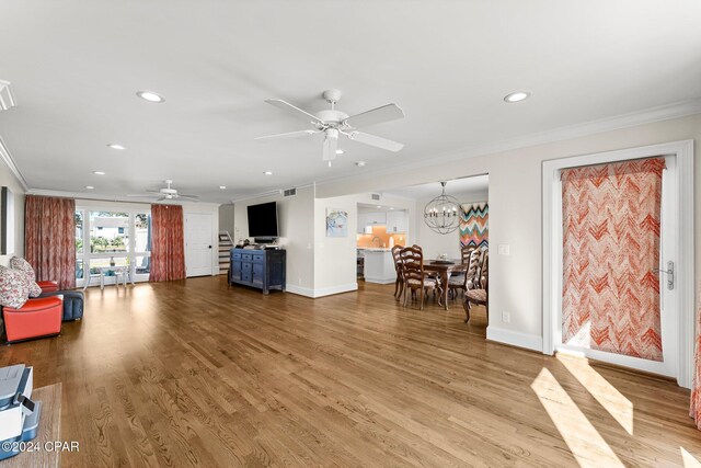 living room with hardwood / wood-style flooring, ceiling fan with notable chandelier, and crown molding