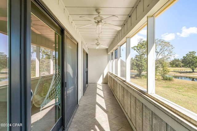 unfurnished sunroom featuring a water view, plenty of natural light, and ceiling fan