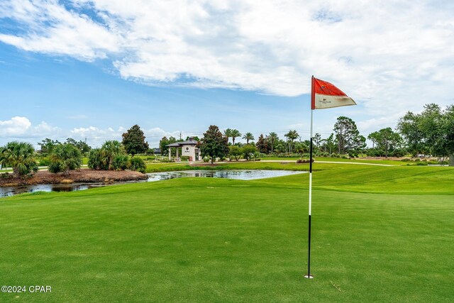 surrounding community with a water view and a lawn