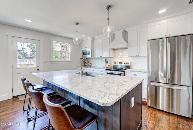 kitchen with custom exhaust hood, sink, an island with sink, and appliances with stainless steel finishes