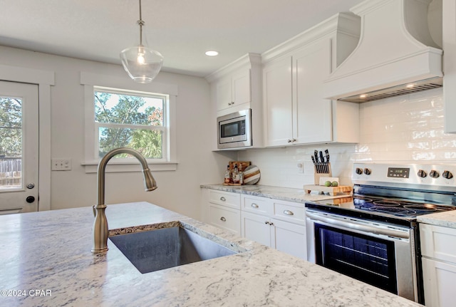 kitchen with a wealth of natural light, white cabinetry, stainless steel appliances, and custom exhaust hood