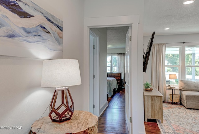 hallway with a textured ceiling and dark hardwood / wood-style floors