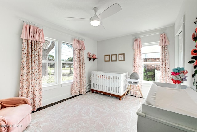 bedroom with ceiling fan, a crib, and light hardwood / wood-style flooring