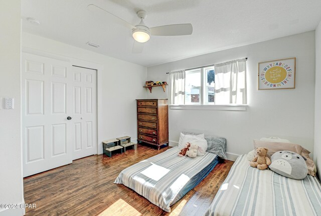 bedroom with a closet, ceiling fan, and dark hardwood / wood-style floors