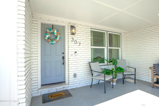 property entrance with a porch and brick siding