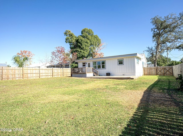 back of house featuring a yard and a wooden deck