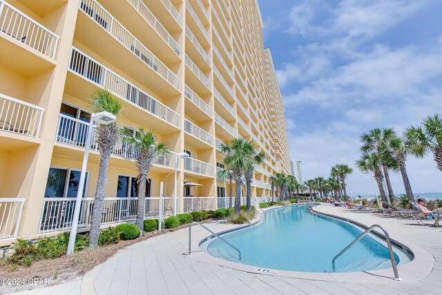 view of patio with a view of the beach, a water view, and a community pool