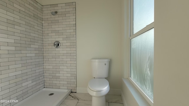 bathroom with a tile shower and toilet