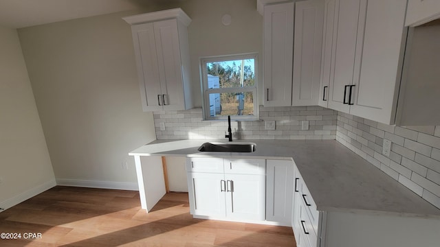 kitchen featuring white cabinetry, sink, backsplash, and light wood-type flooring