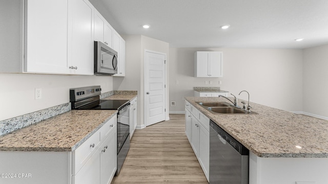 kitchen with white cabinetry, sink, light stone countertops, a center island with sink, and appliances with stainless steel finishes